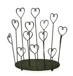 A metal photo/card holder with heart-shaped frames in various sizes arranged on a circular base.