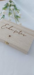A wooden box with the text "Celebrate" engraved on it, surrounded by delicate greenery.