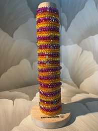 Tall cylindrical jewelry stand, colorful beaded stripes, purple gold orange sequins, decorative display rod.