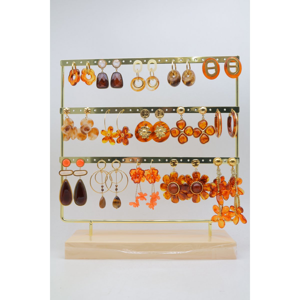 Lot de 15 paires de boucles d'oreilles marron assorties, en acier inoxydable, montées sur un présentoir métallique avec un socle en bois.