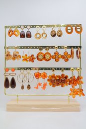 Lot de 15 paires de boucles d'oreilles marron assorties, en acier inoxydable, montées sur un présentoir métallique avec un socle en bois.