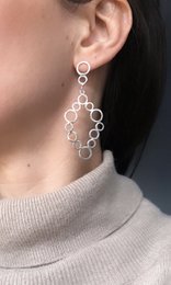 Silver statement earrings with a geometric hexagon design. The earrings feature a cluster of interconnected hexagonal shapes that create a modern, abstract look.
