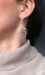 Silver statement earrings with a geometric hexagon design. The earrings feature a cluster of interconnected hexagonal shapes that create a modern, abstract look.