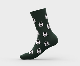  A single organic cotton crew sock featuring a repeating pattern of happy sheep in a dark green color. The sock is available in sizes 35-38, 39-42, and 43-46.