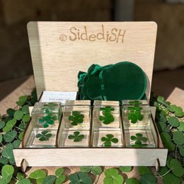  A display of 12 green glass piano-shaped gift tags with a wooden frame and a green frog figurine.
