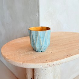 Small stoneware cup with amber-colored interior and textured blue exterior, suitable for hot or cold beverages.