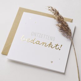 Greeting card with text "Ontzettend bedankt!" in gold foil lettering, accompanied by a dried floral accent.