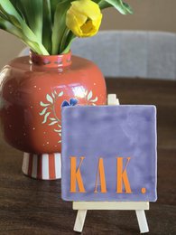 Cream-colored candles in a white box with the text "KAK."