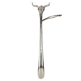 A long, silver-colored metal shoehorn in the shape of a skull with horns, measuring approximately 52 cm in length.