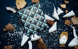  Dark purple chocolate bar with geometric pattern packaging, coconut and cocoa flavored confectionery pieces.