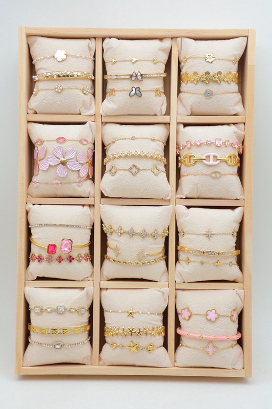 Lot de 36 bracelets en acier inoxydable, répartis sur 12 petits coussins présenté sur un plateau en bois.