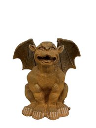  Cast iron garden sculpture of a gargoyle with a fierce, grotesque expression and bat-like wings.