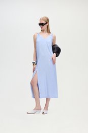  A sleeveless, light blue linen blend dress with a high slit up the side. The dress has a relaxed, casual style.