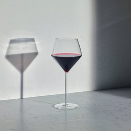 A pair of tall, elegant red wine glasses with a deep red wine filling the glasses.