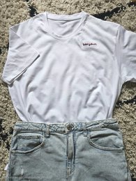  White v-neck t-shirt with 'bonjour' embroidered text, paired with light blue denim jeans.