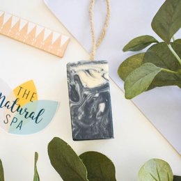 Handcrafted soap on a rope with a dark, marbled design. Made with natural ingredients and packaged in a paper wrap.