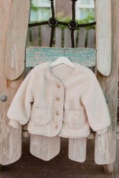 Soft, cozy beige teddy jacket for kids, available in sizes 18M to 7Y. Features a button-up closure and warm, plush fabric perfect for cold weather.
