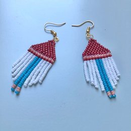 Handmade, statement earrings in a vibrant red, white, and blue color palette. The earrings feature a triangular shape with beaded fringe detailing, creating a bold and eye-catching accessory.