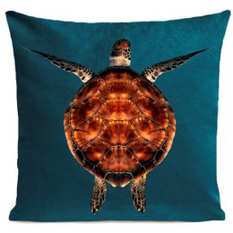 A decorative cushion featuring a vibrant turtle design in shades of brown and orange against a deep teal background. The cushion has a square shape and measures 60x60cm or 40x40cm, with color variants in blue duck and green.
