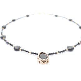 The necklace features a black onyx pendant with a delicate chain made of black and gray beads. The pendant has a unique, intricate design that adds a touch of elegance to the piece.