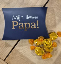  A navy blue box filled with golden toffee candies, with the text "Mijn lieve Papa!" printed in gold on the box.