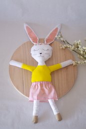 A DIY box containing a handmade rabbit doll with white fur, pink ears, and a yellow dress.