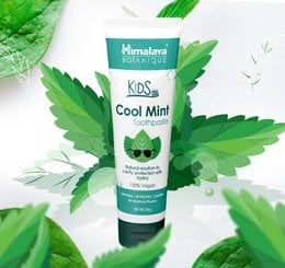 Cool mint flavored toothpaste for kids, white tube with teal cap, natural ingredients with mint leaves and pomegranate.