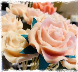 A bouquet of 5 delicate, pastel-colored roses made of fondant, a type of sugar-based icing often used in cake decorating. The roses have a soft, velvety appearance and are accented with green leaves.