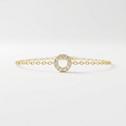 Gold-toned charm bracelet with a single circular charm.