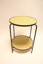Round side table with woven webbing top and bottom shelf in a modern, minimalist design.