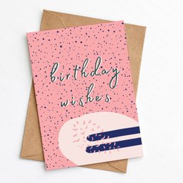 A pink birthday card with a polka dot pattern and the text "birthday wishes" written in cursive. The card has a simple, minimalist design and appears to be made of high-quality materials.