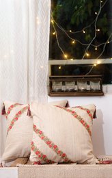 Ivory handwoven cushion cover with coral geometric stripe pattern, textured natural fiber material, square shape.