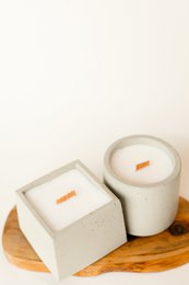 Oval and quadrat-shaped pillar candle in a neutral concrete color. The candle has a simple, minimalist design that would complement a variety of home decor styles.