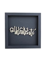 A wooden frame card with the text "MOMENTS OF HAPPINESS" in various colors including altrosa, taubengrau, taupe, eosin, aubergine, petrol, rehbraun, dunkelgrau, and schwarz.
