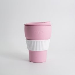 A foldable, reusable coffee cup made of durable silicone material in a soft pink color. The cup features a textured grip and a snap-on lid for easy transport.