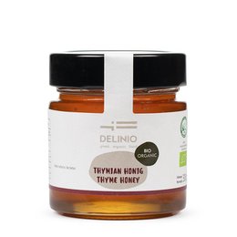 Organic thyme honey in a glass jar. The honey has a rich, golden color and a smooth, creamy texture. The jar features a simple, minimalist label design with the product name and brand logo.