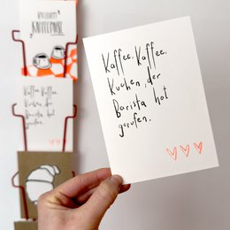 A handwritten card with the text "Kaffee, Kaffee, Kaffee, der Barista hat gewonnen." The card features three red heart shapes drawn on the side. The card appears to be a friendship card for a barista or coffee lover.