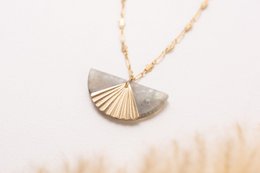 Elegant pendant necklace featuring a fan-shaped metal charm on a delicate gold chain. Suitable for casual or formal wear.
