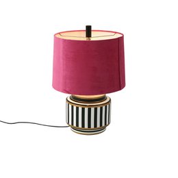 Pink velvet drum shade table lamp with black white striped ceramic base, modern design.