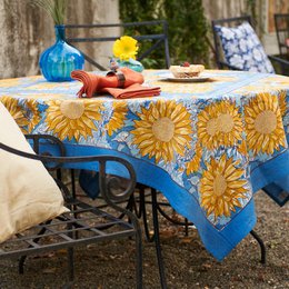 A vibrant, sunflower-patterned tablecloth in shades of blue, yellow, and orange. The tablecloth features a bold, floral design that would be perfect for an outdoor dining setting or summer gathering.