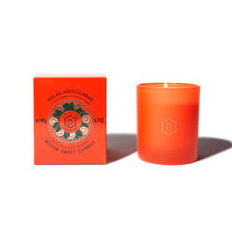 A round, tall orange candle with a floral design on the label. The candle is scented and comes in a red box.