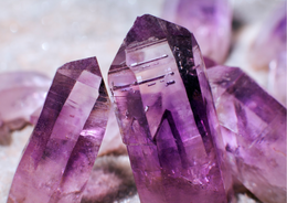 Amethyst gemstone points in shades of purple and lavender, with a crystalline structure.