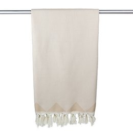 Organic cotton hammam towel in beige color with tasseled edges, suitable for use in bathrooms or spas.