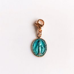 Turquoise oval pendant with a miraculous medal design. Made of metal with a gold-tone finish.