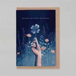  A whimsical Mother's Day card featuring a hand reaching up to touch a delicate blue flower against a dark background with other floral elements.