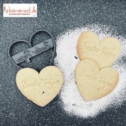 Heart-shaped baking decorations with "Best Dad" text, made of light-colored dough and dusted with powdered sugar.
