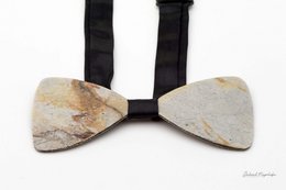 A stylish, wooden bow tie in a natural, earthy tone. The bow tie features a unique, geometric pattern that adds a modern touch to the classic accessory.