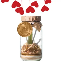 Ginger lemon rum preparation in a glass jar with dried citrus slices and a wooden label.
