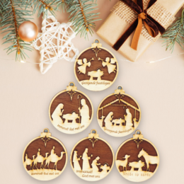 Set of 6 wooden Christmas ornaments with laser-cut nativity scene designs in a variety of shapes and sizes. Includes round, oval, and star-shaped ornaments in a warm brown color with white cutouts depicting the nativity.