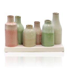 Multicolored ceramic bottle vases in pink, green, beige on white tray, various heights and shapes